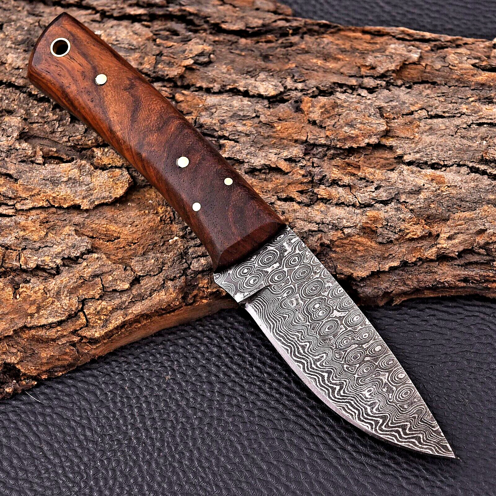 Close-up of handmade Damascus steel knife showing detailed blade pattern and hardwood handle